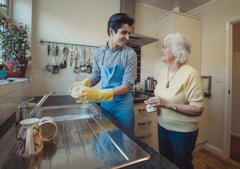 Young man helping elderly woman with washing up