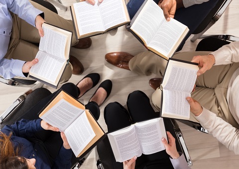 People in a circle holding open books