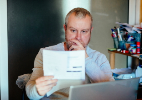 Man studying sheet of paper and laptop