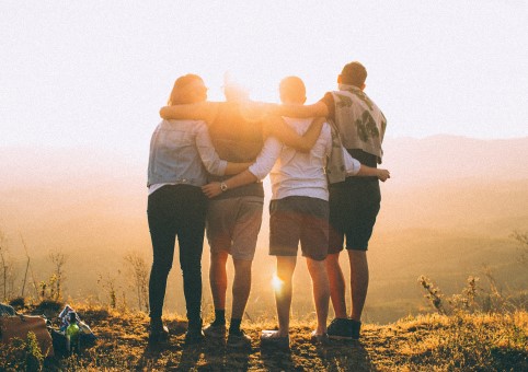 Teen friends standing in front of a sunset