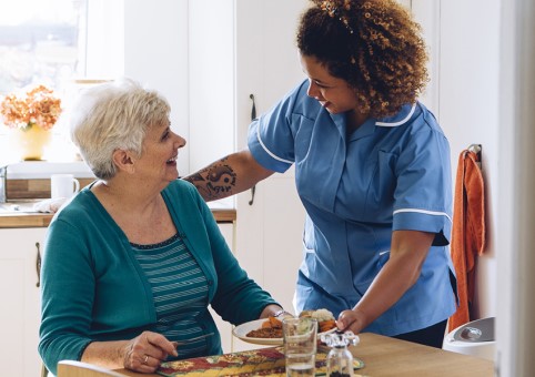 Carer helping woman with her meal