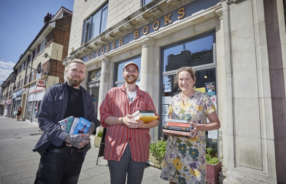 People holding books in front of a shop