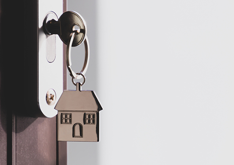 A key with a house-shaped keyring in a door 