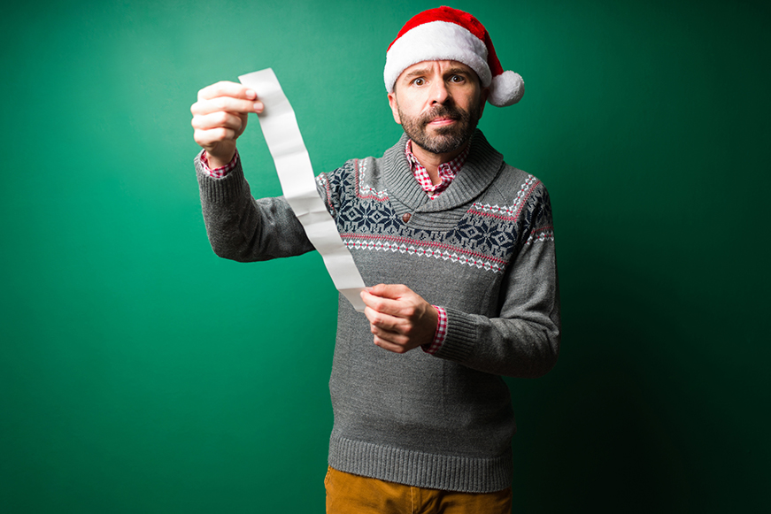 Man in Christmas clothing looking shocked at a bill