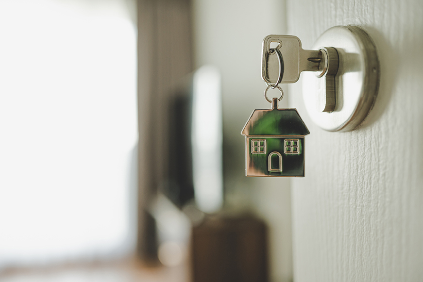 A key in a door lock attached to a house-shaped keyring A key in a door lock attached to a house-shaped keyring