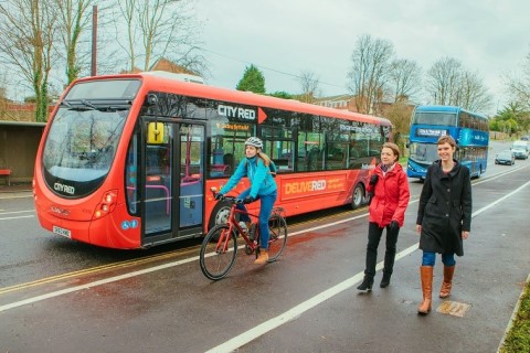 Buses, a cyclist and some pedestrians
