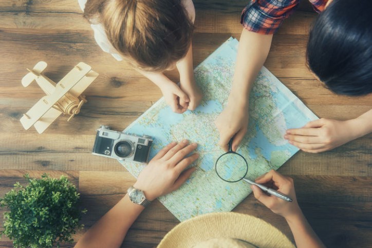 Three people looking at a map with a magnifying glass and a camera