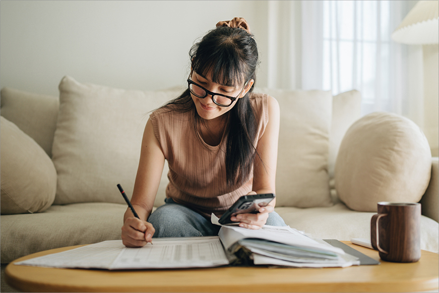 A happy woman doing her accounts in her living room A happy woman doing her accounts in her living room