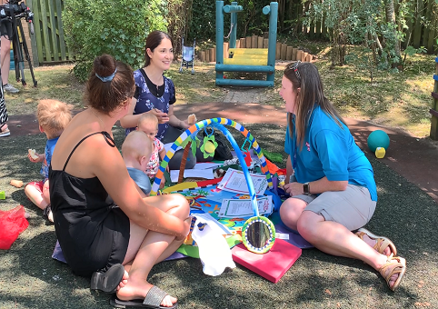 Young mothers sitting on grass with babies