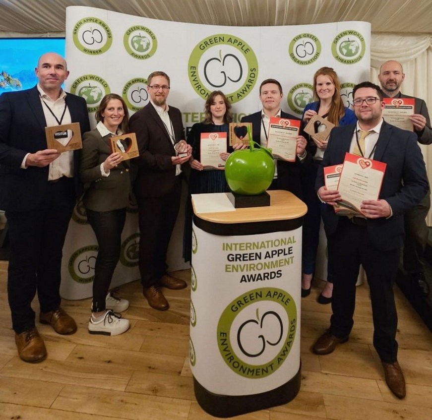 A group of award winners showing off their awards at the International Green Apple Environment Awards