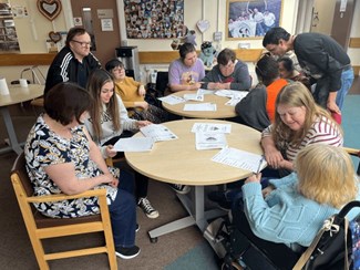 Photo of a group of service users filling out the VoiceAbility survey forms