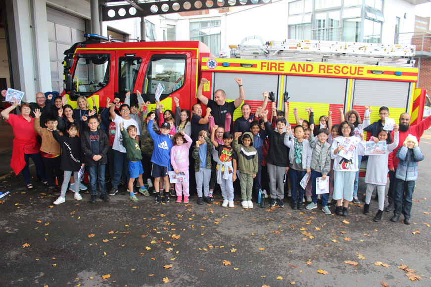The Junior Neighbourhood Wardens cheering in front of a fire engine