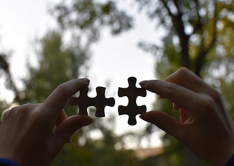 A person holding two pieces of a puzzle