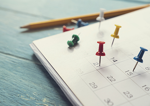 A calendar with a pencil and some tacks